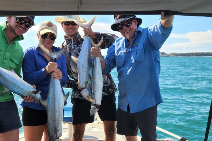 a group of people standing next to a person holding a fish