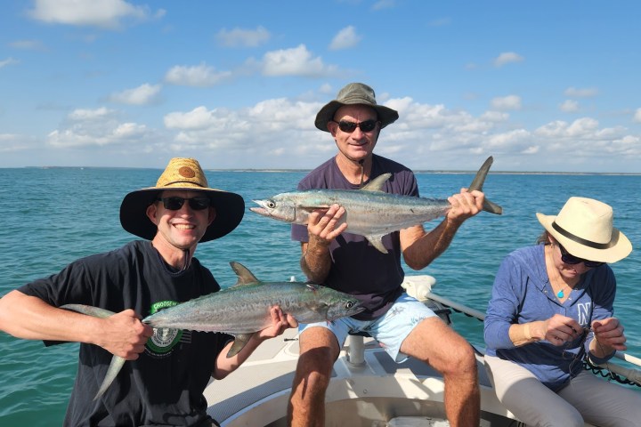 a person holding a fish on a boat in a body of water