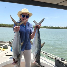 a person holding a fish on a boat in a body of water