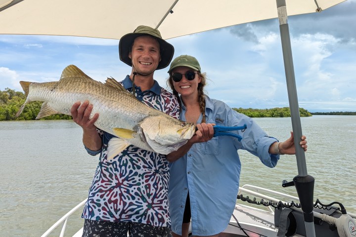 a person holding a fish on a boat in a body of water