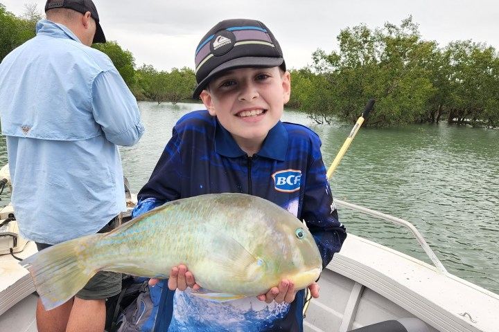 a young boy holding a fish in the water
