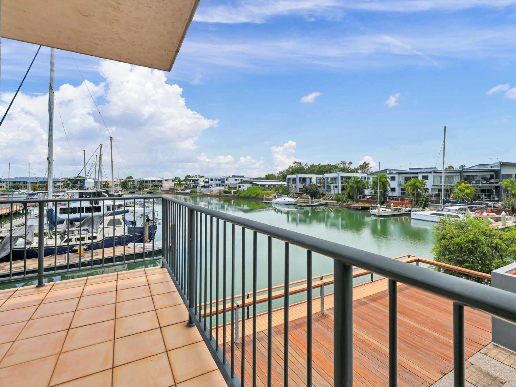 Balcony view of marina with boats, blue sky, and clouds.