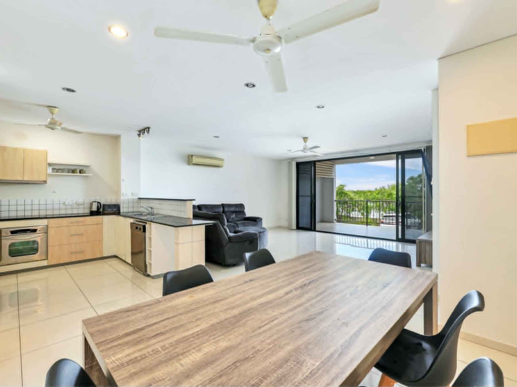 Modern open-plan kitchen and living area with dining table and large windows.