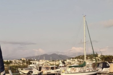 Boats docked in a marina with mountains in the background.