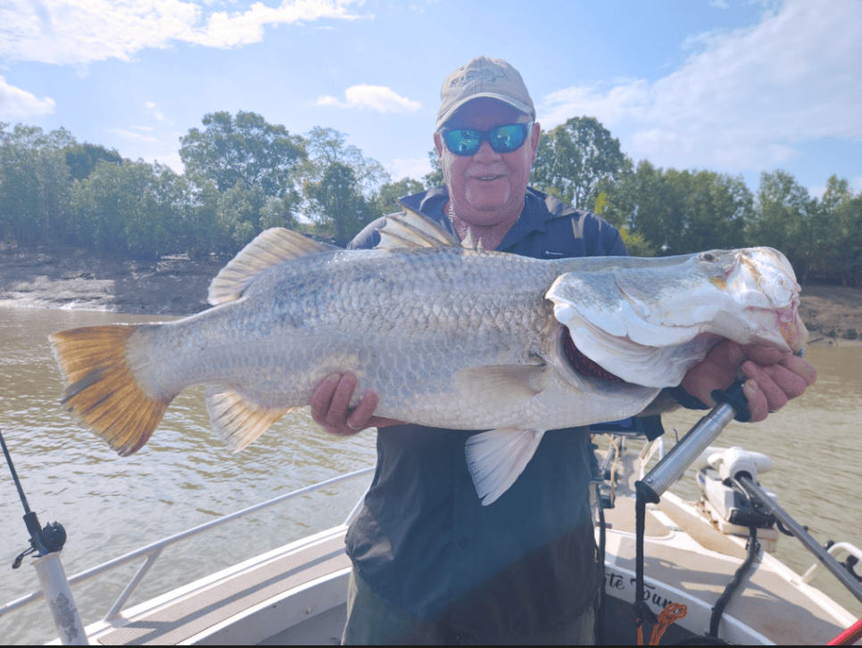 Man holding large fish on a boat in a river setting.